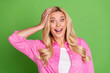 © deagreez - Cheerful Young Woman in a Pink Shirt Showing a Surprised Gesture Against a Vibrant Green Background