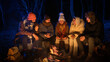 © kinomaster - Friends sitting around a campfire in the woods on a winter evening