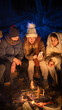 © kinomaster - Friends sitting around a campfire in the woods on a winter evening