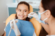 © Prostock-studio - Dental care prevention and treatment procedure. Millennial female doctor in protective mask and gloves holds medical instrument and checks oral cavity of little smiling girl in modern clinic interior