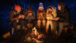 © kinomaster - Friends sitting around a campfire in the woods on a winter evening