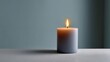 © CYBERPINK - Close-up of a single white candle on a grey surface. the candle is lit, with the flame burning brightly. the background is a light blue color, and the focus is on the candle.