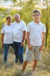 © Serhii - Grandson, grandfather and grandmother sitting on grass having fun outdoors in park at sunset