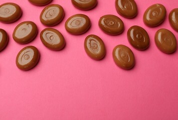 Wall Mural - many tasty caramel candies on pink background, flat lay. space for text