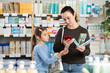 © JackF - Woman stands near the counter with her daughter in a pharmacy and scans a mobile set of toothbrushes in a pharmacy. Buyer pays for purchases through a mobile application using a QR code