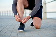 © MollerFinest/peopleimages.com - Man, athlete and tie shoelace by beach, sports preparation and outdoor for marathon training. Male person, sneakers and getting ready for cardio challenge on sea promenade, runner and start workout