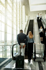 Poster - Escalator, airport and business people in lobby for travel, commute and arrival with luggage. International trip, conference and back of man and woman walking for convention, meeting and seminar