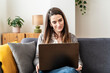 © Westend61 - Woman working on a laptop at home on a sofa