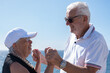© luciano - Carefree senior couple enjoys a beautiful day by the ocean, hugging each other with smiles. Background of rocky coastal landscape, a perfect scene of love, companionship and happiness in retirement
