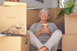 © luciano - Happy senior woman involved in moving house sitting among cardboard boxes having a pause, concept of relocating, retirement, new life, buying, renting, apartment, house