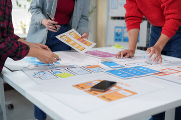 Wall Mural - ui and ux designers are reviewing mobile application layouts, discussing user interface and user exp