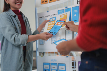 Wall Mural - two designers examining and discussing the user interface and user experience of a new mobile applic