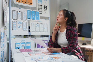 Wall Mural - young professional web designer reviewing mobile application wireframes, contemplating design improv