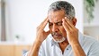 © aukkasit - Elderly man suffering from severe headache at home holding his temples in pain