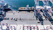 © Monet_P - High-angle view of towering shipping cranes moving containers from a large cargo ship docked at a seaport. The deep blue ocean and colorful containers create a dynamic logistics scene.