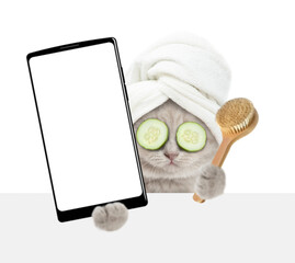 Leinwandbilder - Cute tiny kitten with towel on it head holds  shower brush and big smartphone with white blank screen in it paw above blank white banner. isolated on white background