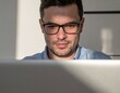 © Masrur - Corporate close-up portrait of a professional with glasses working on a laptop, indoor workspace with soft shadows and focused light