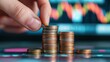 © oksa_studio - Hand placing coin on growing stacks symbolizing savings growth and investment
