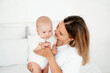 © Any Grant - mom and baby, a young beautiful mother with a little boy hugging at home in the bedroom, maternal care and love, portrait of a happy mother with a child, healthy motherhood.