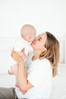 © Any Grant - mom and baby, a young beautiful mother with a little boy hugging at home in the bedroom, maternal care and love, portrait of a happy mother with a child, healthy motherhood.