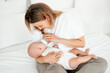 © Any Grant - mom feeds the baby with a bottle of milk or formula, feeding the baby in her arms, a young mother feeds the newborn baby at home on the bed