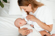 © Any Grant - mom feeds the baby with a bottle of milk or formula, feeding the baby in her arms, a young mother feeds the newborn baby at home on the bed