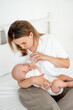 © Any Grant - mom feeds the baby with a bottle of milk or formula, feeding the baby in her arms, a young mother feeds the newborn baby at home on the bed
