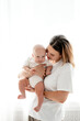 © Any Grant - happy mom with a newborn baby on a white isolated background, space for text, mom hugs and kisses her baby while holding him in her arms, happy motherhood