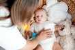 © Any Grant - mom and baby, mother puts a newborn baby to sleep in a crib, playing with a rattle, maternal care and love, portrait of a happy mother with a child