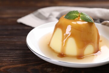 Wall Mural - delicious pudding with caramel sauce and mint on wooden table, closeup