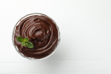 Wall Mural - delicious chocolate pudding with mint on white wooden table, top view. space for text