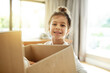 © Moller/peopleimages.com - Portrait, real estate and happy kid with box in new house, unboxing or pack for relocation to dream property. Face, moving or girl child with cardboard for donation, storage or carry toys for charity