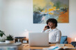 © Studio Marmellata - An Arab young man works from home. He is on a call while using his laptop at his desk.