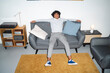 © Studio Marmellata - An Arab young man is relaxing on a gray sofa in a modern living room. He is smiling and has his arms outstretched on the back of the couch.