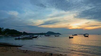 Wall Mural - Time lapse the sky is painted with shades of yellow oranges 
and the clouds are highlighted with a soft golden hue, 
making them look like fluffy blankets of color floating above the sea surface.
