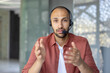 © Liubomir - A man wearing a headset gestures while looking directly at the camera. He seems to be in a video conference call, or an online meeting.