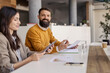 © Dusan Petkovic - Happy bearded businessman sitting at office next to colleague with paperwork in hands and smiling at camera.