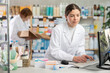 © JackF - Young pharmacy intern works at a computer against the background of a qualified pharmacist. Women pharmacists work in a European pharmacy