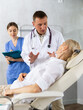© JackF - Male doctor and female assistant having conversation with elderly woman patient about need for additional diagnostic procedures, long-term and comprehensive treatment, assistant records data in report