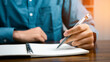 © ภาคภูมิ ปัจจังคะตา - Male hand taking notes on the notepad. businessman working at work table, checklist writing planning investigate enthusiastic concept. focus on man hand holding pen, putting signature at official pape