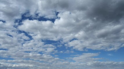 Wall Mural - Time lapse of white to gray clouds moving through a bright blue summer sky. Isolated to sky only.
