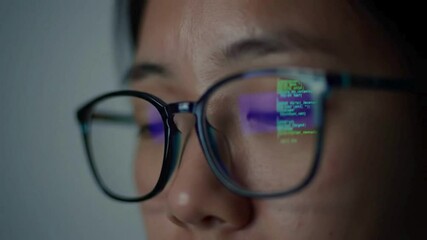 Coding reflection in glasses of programmer working on computer screen