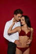 © LIGHTFIELD STUDIOS - Passionate couple embracing in alluring intimacy against a deep red background