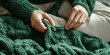 © Inspire Shots Hub - Close-up of hands knitting a green wool sweater, showcasing texture and craftsmanship, representing handmade, comfort, and warmth