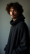 © Ernesto - Comforting portrait of man in knit poncho, angled back view. Plush texture, curly hair, and warm lighting create ultimate cozy aesthetic.