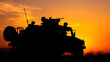 © Zachary - Military patrol car on sunset background. Army war concept. Silhouette of armored vehicle with soldiers ready to attack,