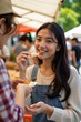 © kineter_ai - Local Delicacies: Asian Woman Sampling Gourmet Cheese from Friendly Market Vendor's Stall (Partial View)