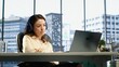 © DC Studio - Young entrepreneur listening to a podcast while she solves daily business tasks in high end office, corporate success story. Female director working with headphones, determination. Camera A.