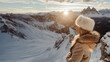 © Darya - Woman in winter coat admiring snowy mountain landscape at sunrise. Nature appreciation concept.