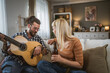 © Miljan Živković - Adult couple enjoy at home play guitar and drink beer happy together